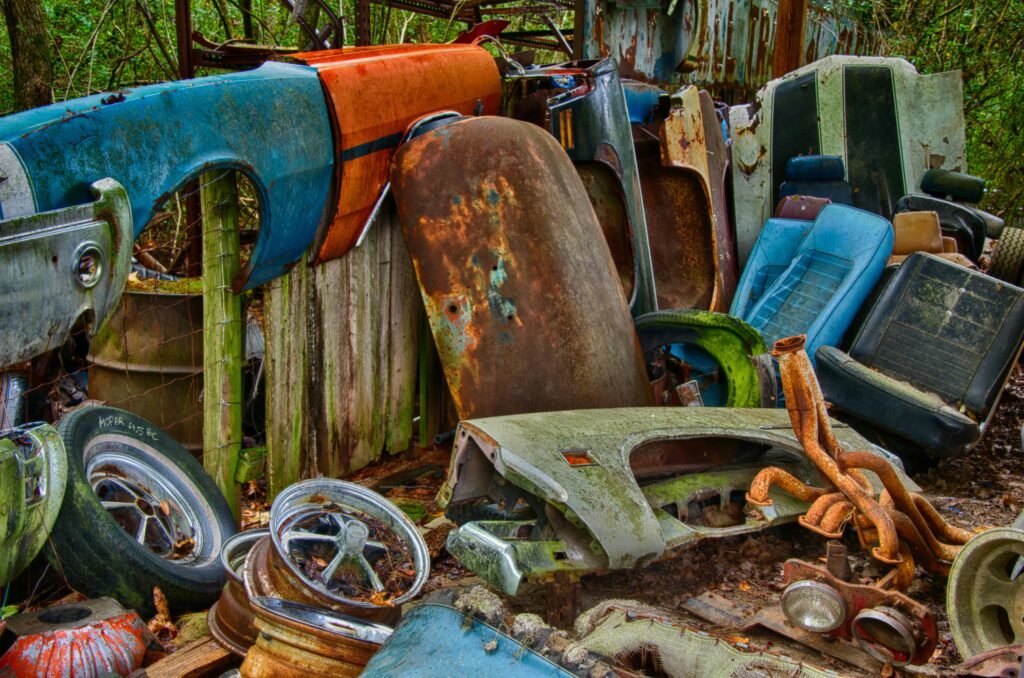 A collection of rusting vintage car parts in an outdoor junkyard, evoking nostalgia.